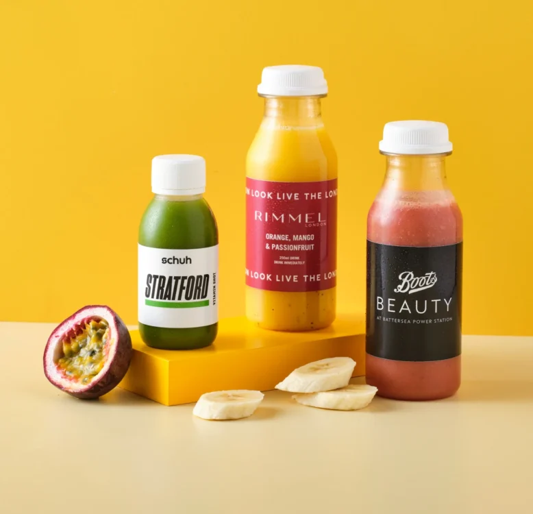A collection of juice shots, juice bottles and smoothie bottles with branded labels